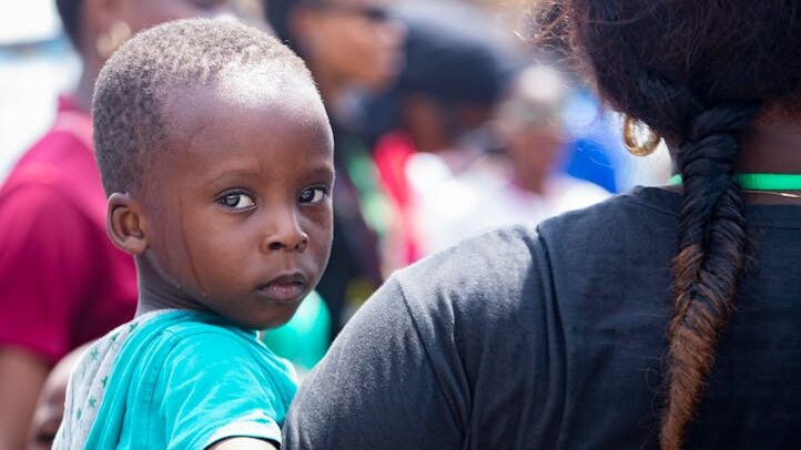 A child held by a volunteer during a community event outdoors, showcasing care.